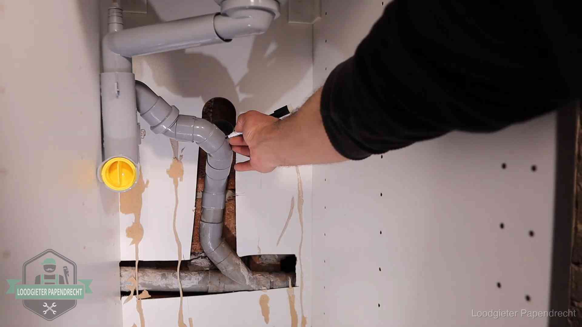 Loodgieter markeert een pvc-afvoerbuis onder een gootsteen in Papendrecht