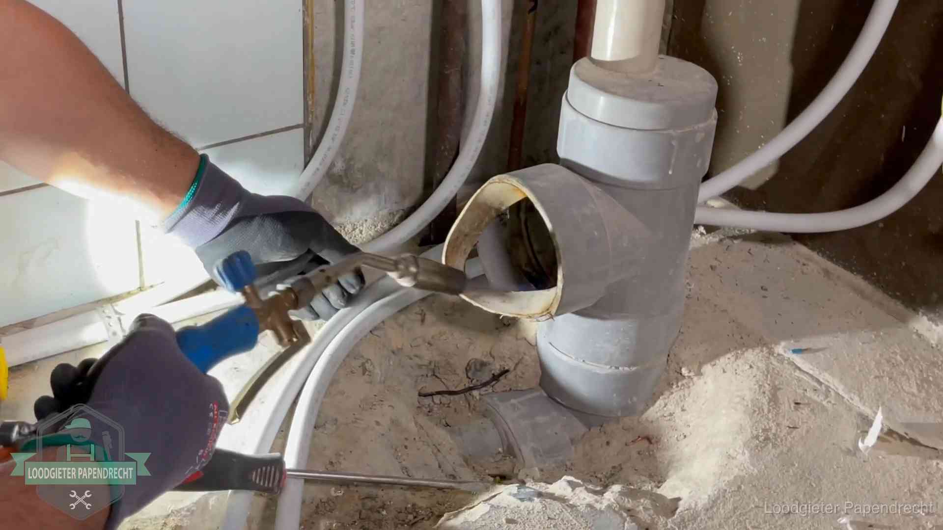 Loodgieter werkt met brander en messing kraanwerk aan leidingen in Papendrecht