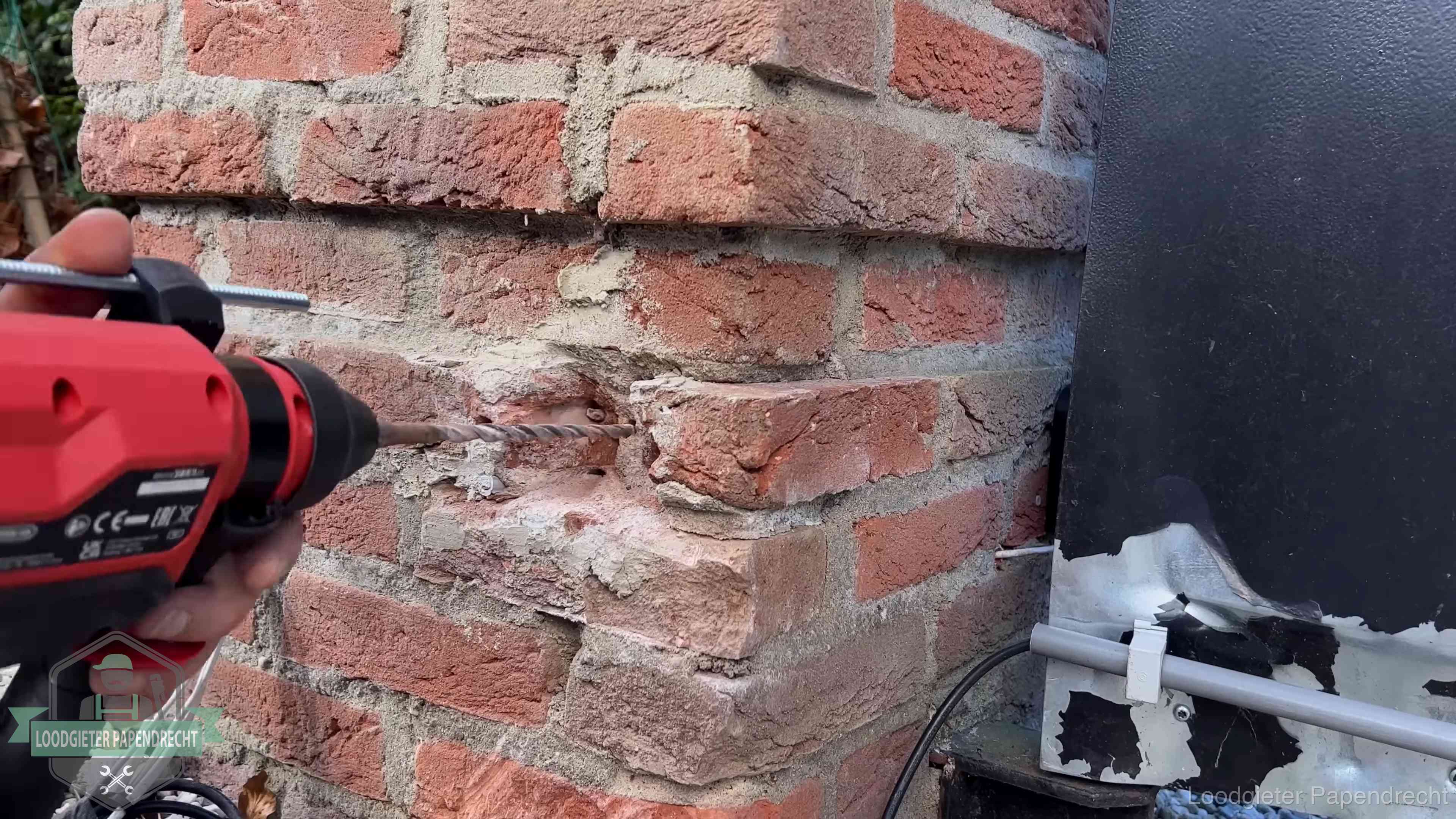 Vakman boort in de buitenmuur van een woning in de regio Papendrecht