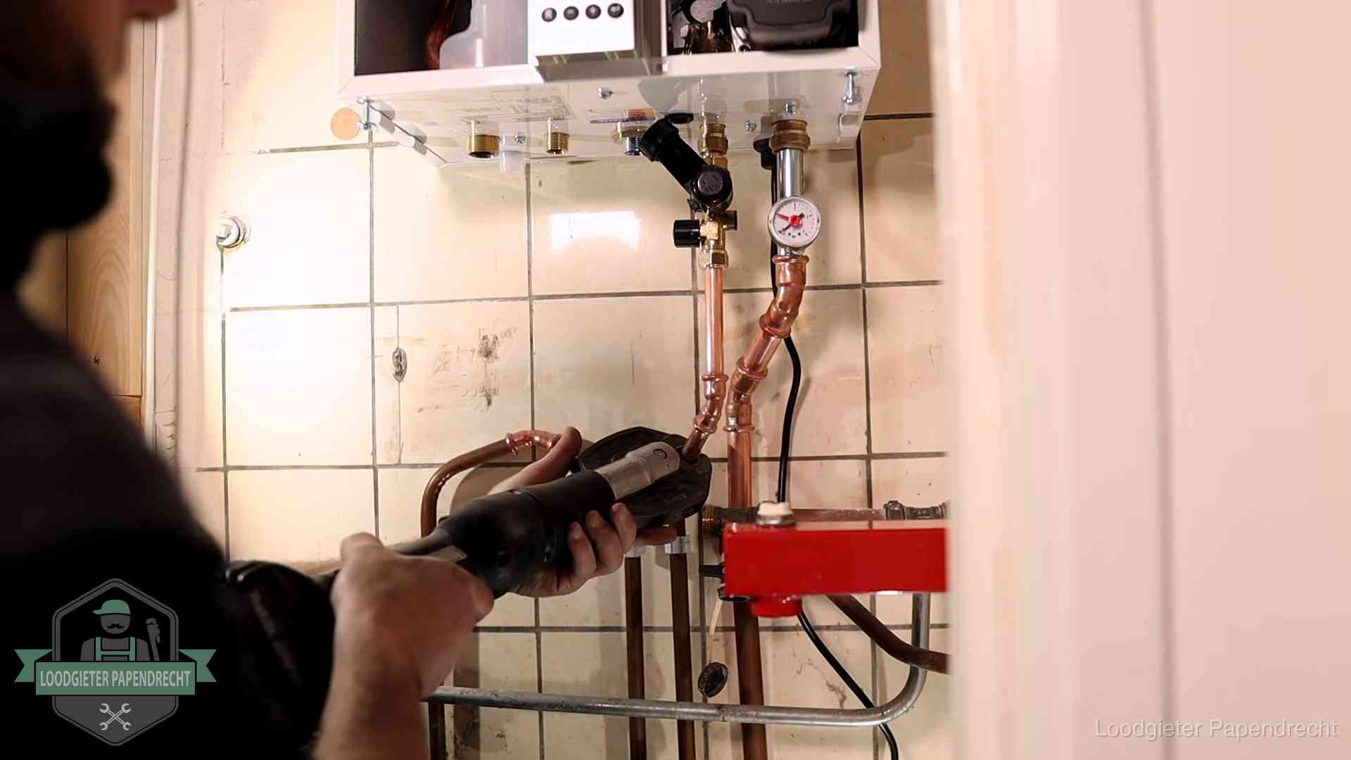 Monteur werkt aan de leidingen onder een cv-ketel in Papendrecht