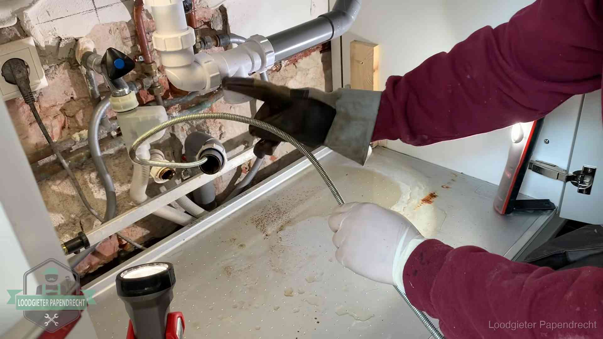 Ontstoppingsveer gaat in een geopende sifonaansluiting onder het aanrecht in Papendrecht