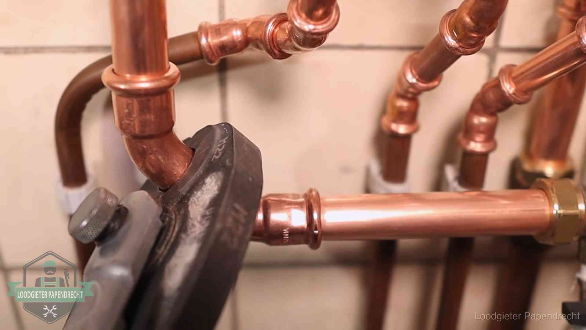 Persmachine perst een koperen fitting op nieuw leidingwerk in Papendrecht