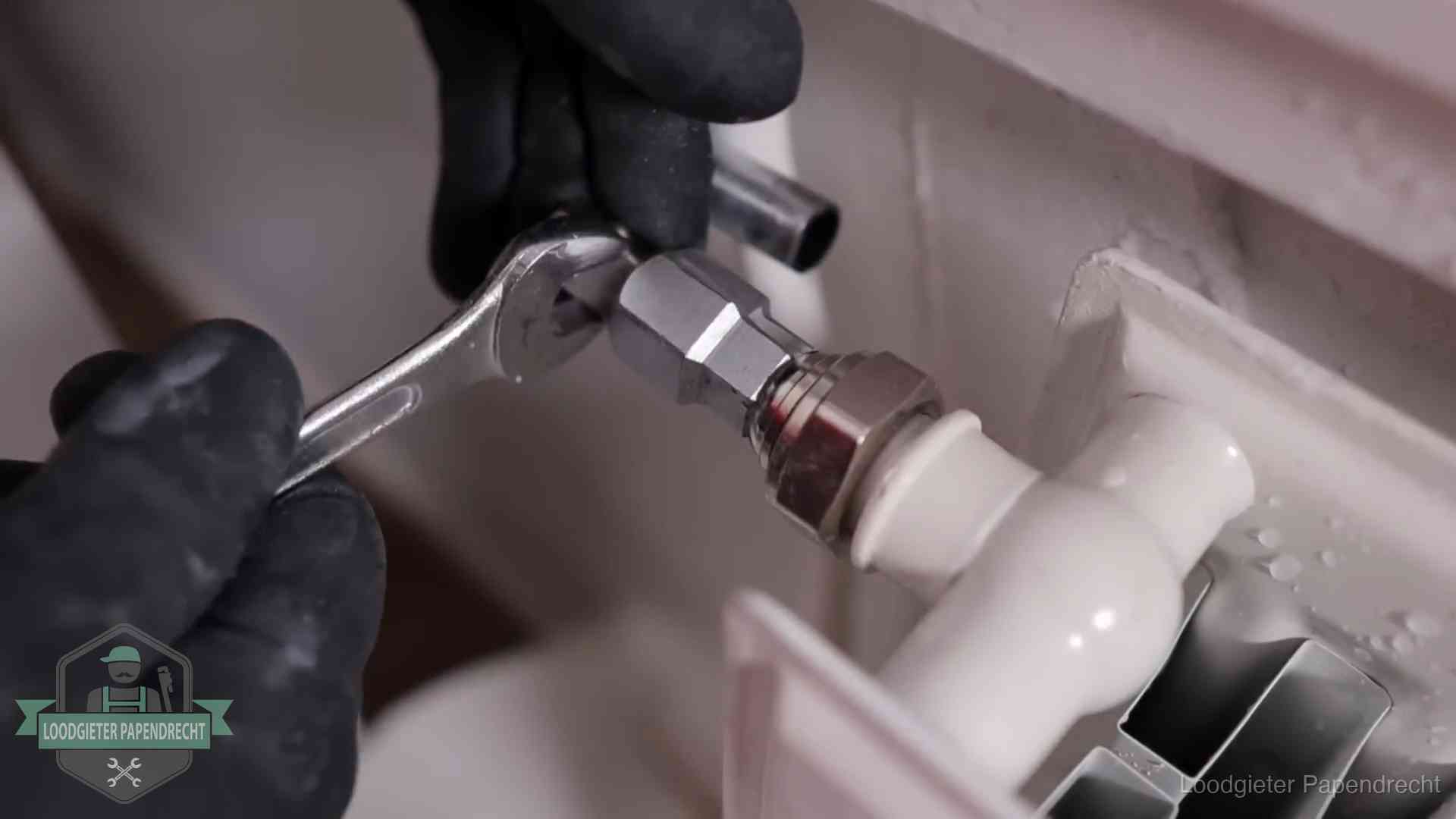 Steeksleutel draait een wartelkoppeling op een radiatorkraan aan in Papendrecht