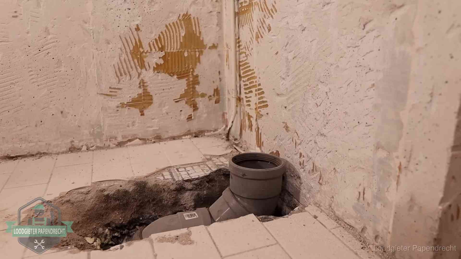 Opengebroken vloer met een nieuwe pvc-rioolbocht in een gegraven sleuf in Papendrecht
