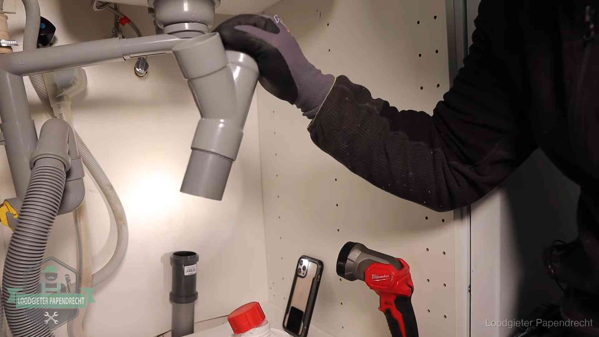 Loodgieter demonteert het sifon- en afvoerwerk onder een gootsteen in Papendrecht bij stankklachten