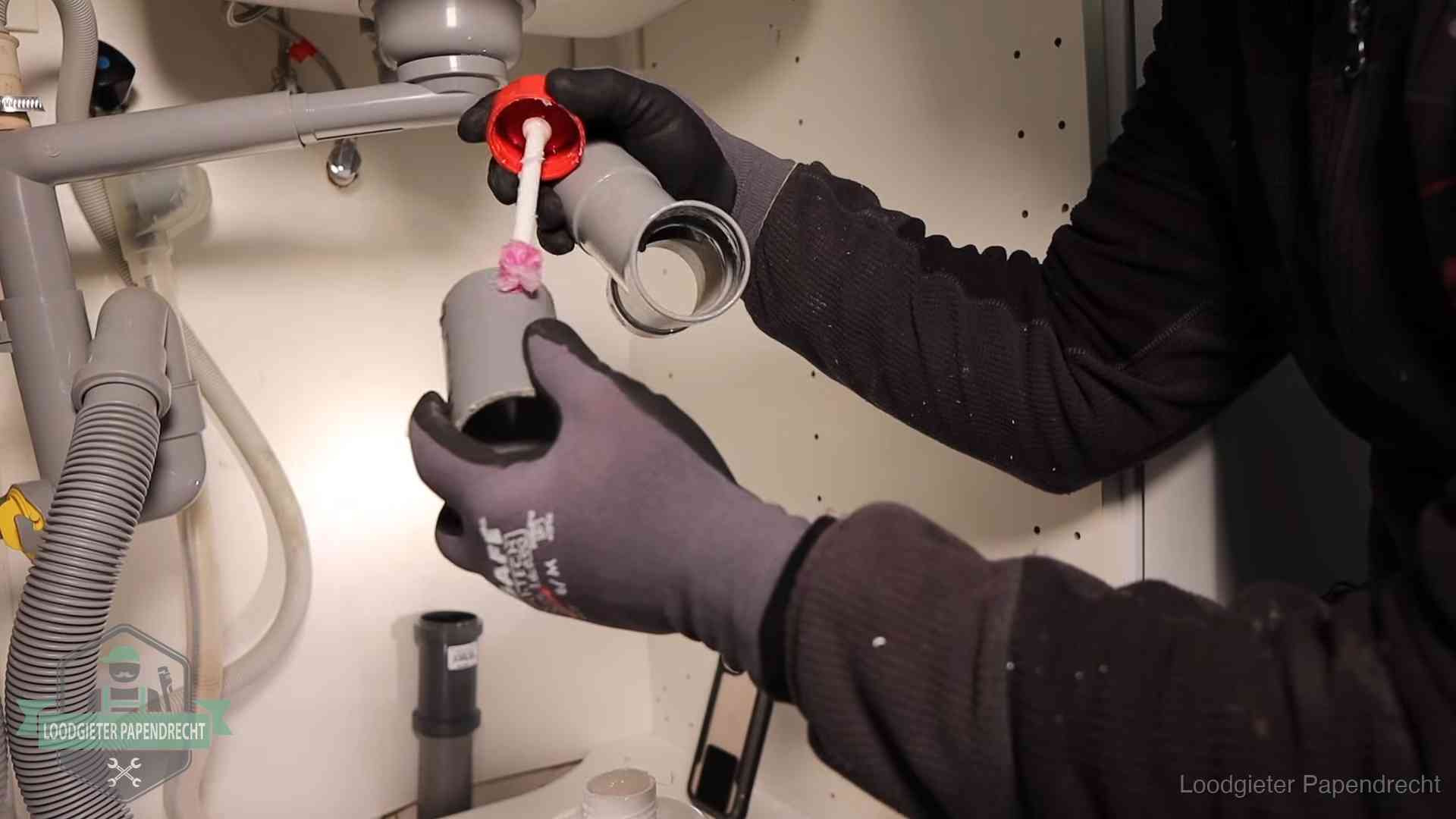 Loodgieter demonteert en reinigt de sifon onder een keukenkast in Papendrecht