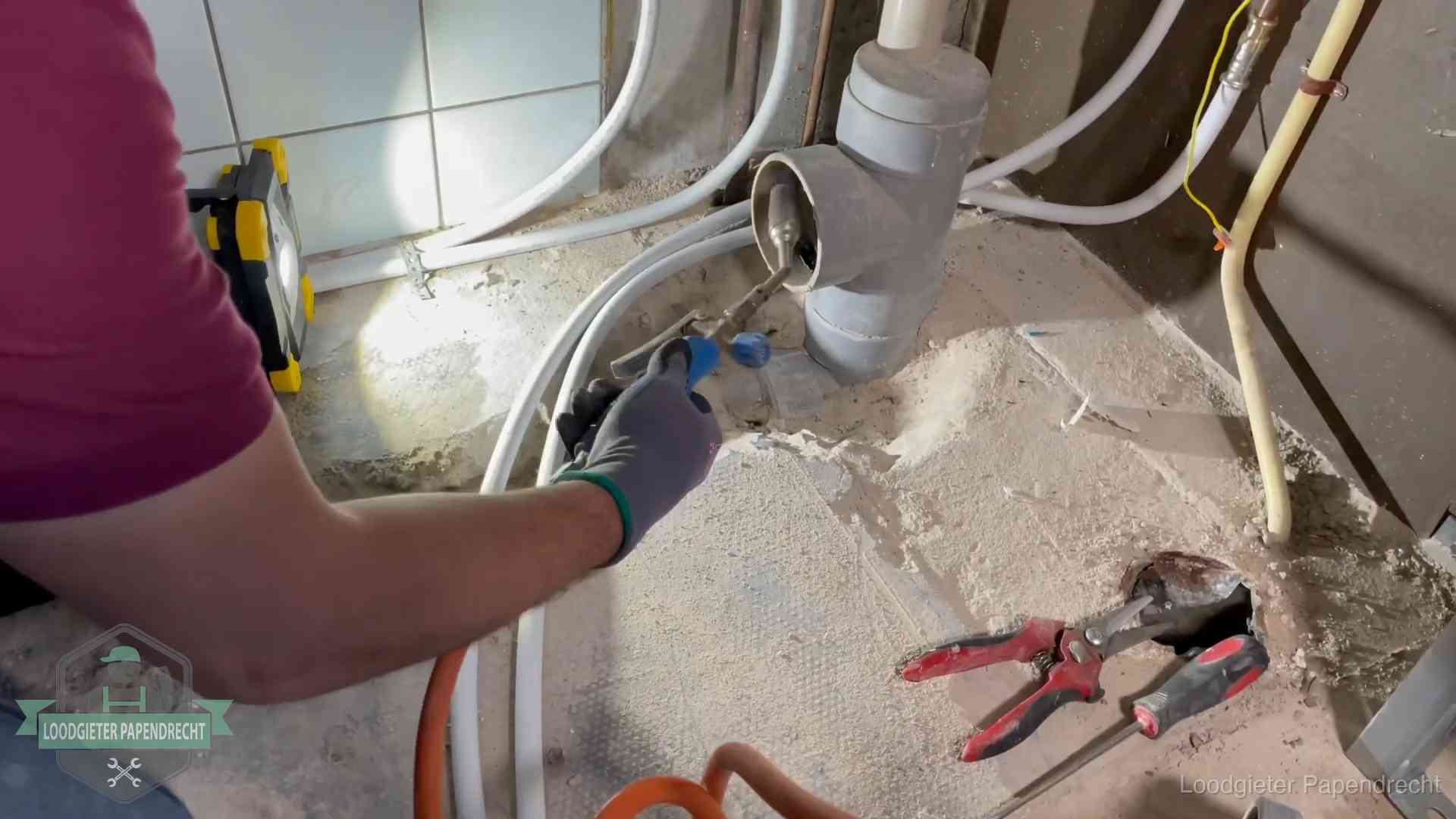 Loodgieter werkt aan leidingen bij een pvc-standleiding in een appartement in Papendrecht